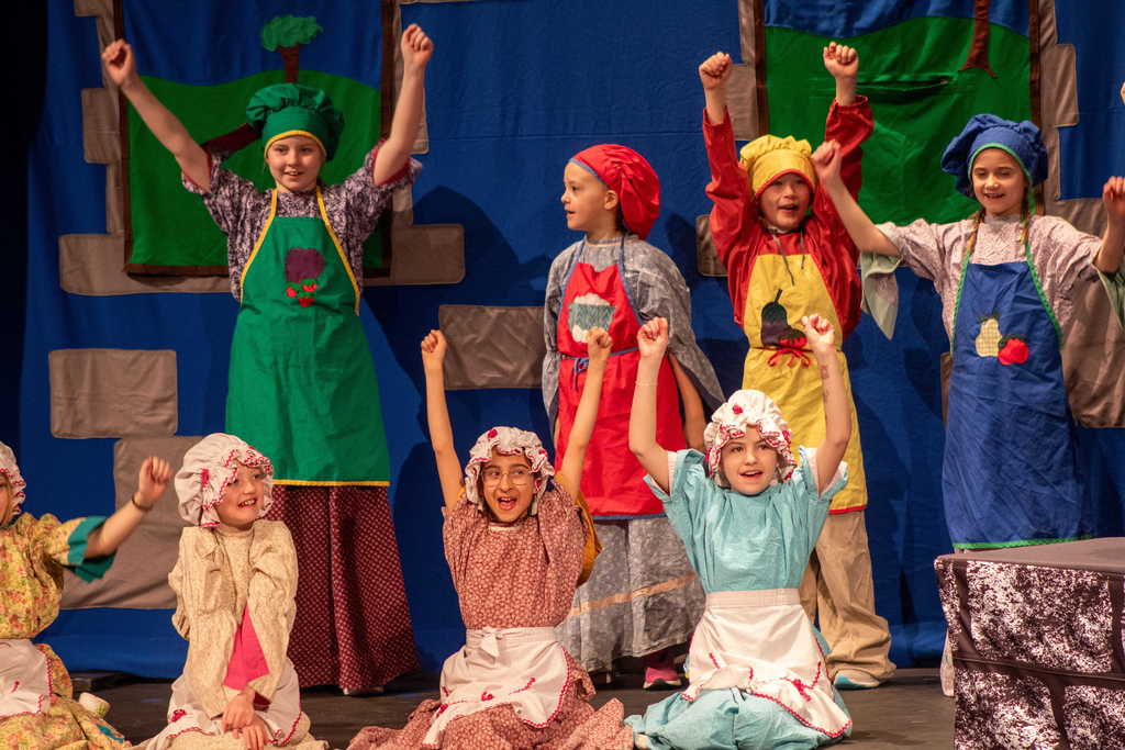 Students dressed as maids and cooks holding hands up excitedly 