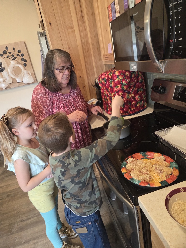 Young boy and girl helping teacher prepare food on the stovetop