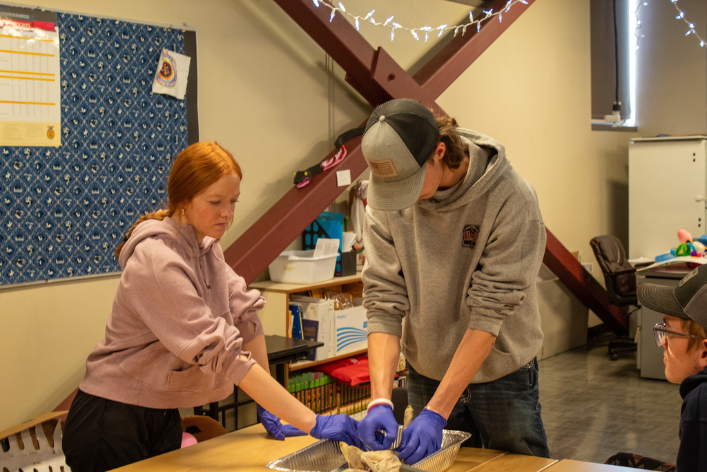 two high school students standing over desk completing project