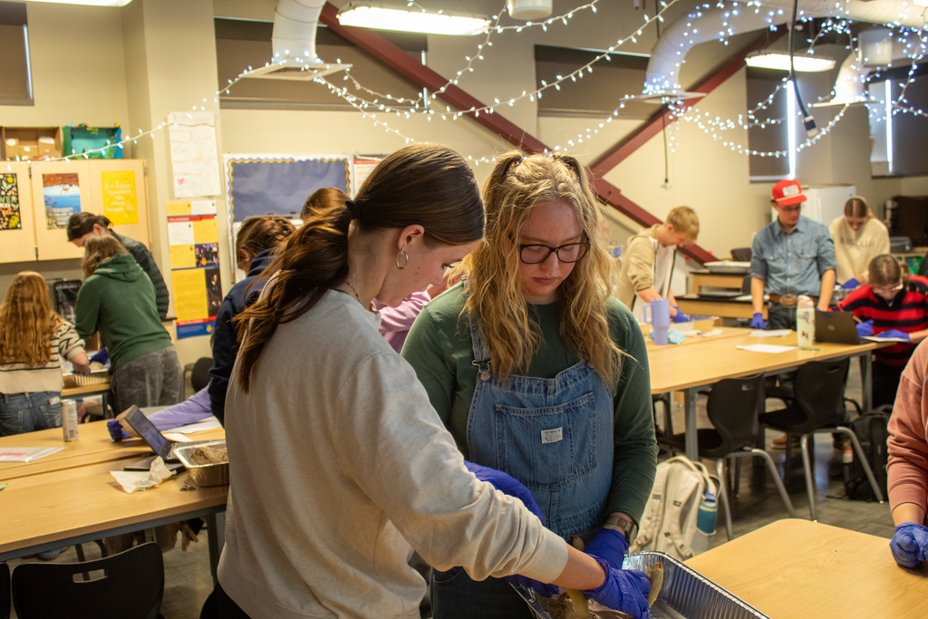two high school students standing over desk