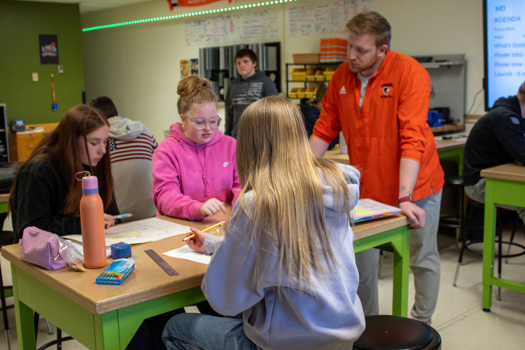 Group of three young ladies working with teacher on poster project