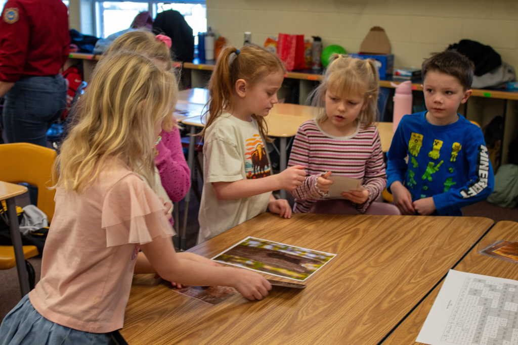 Four young students analyzing a picture laying on a desk