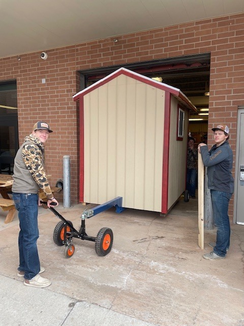 Two young men working together to move shed