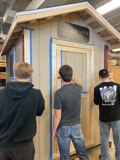 Three young men painting a shed