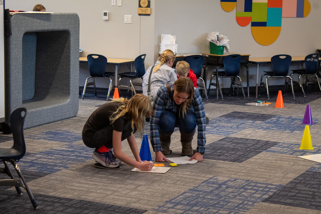 Families sitting on the ground in circles filling out worksheets