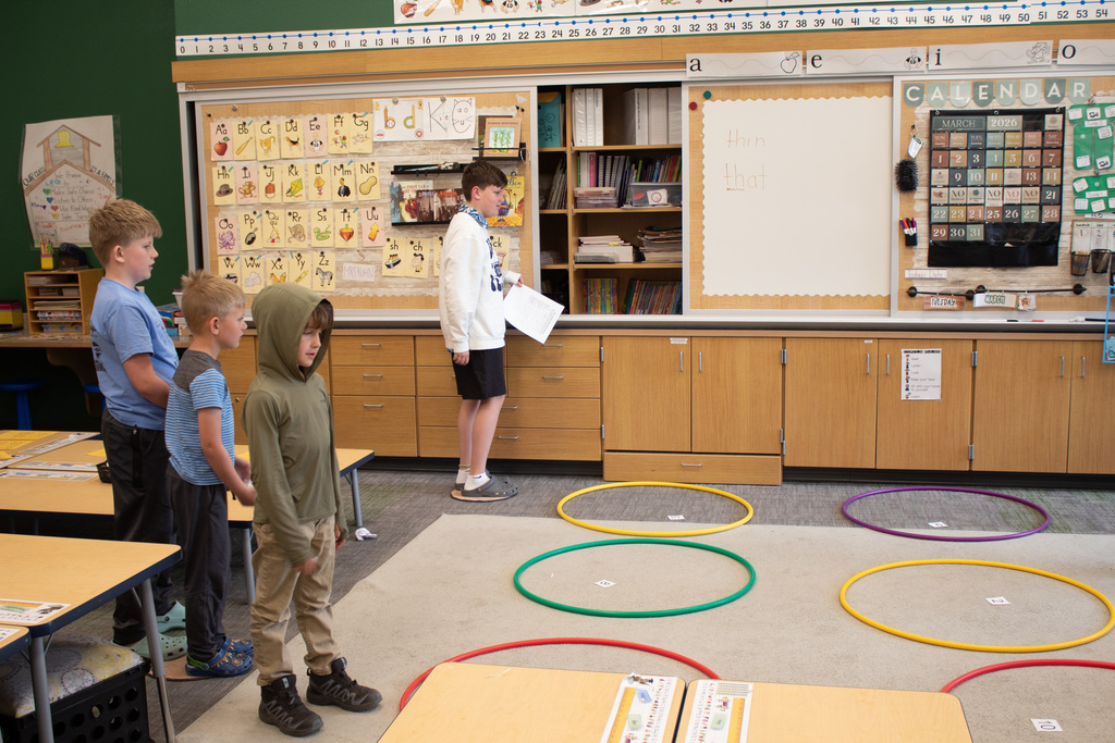 Four young boys throwing paper balls into a hula hoops on the ground