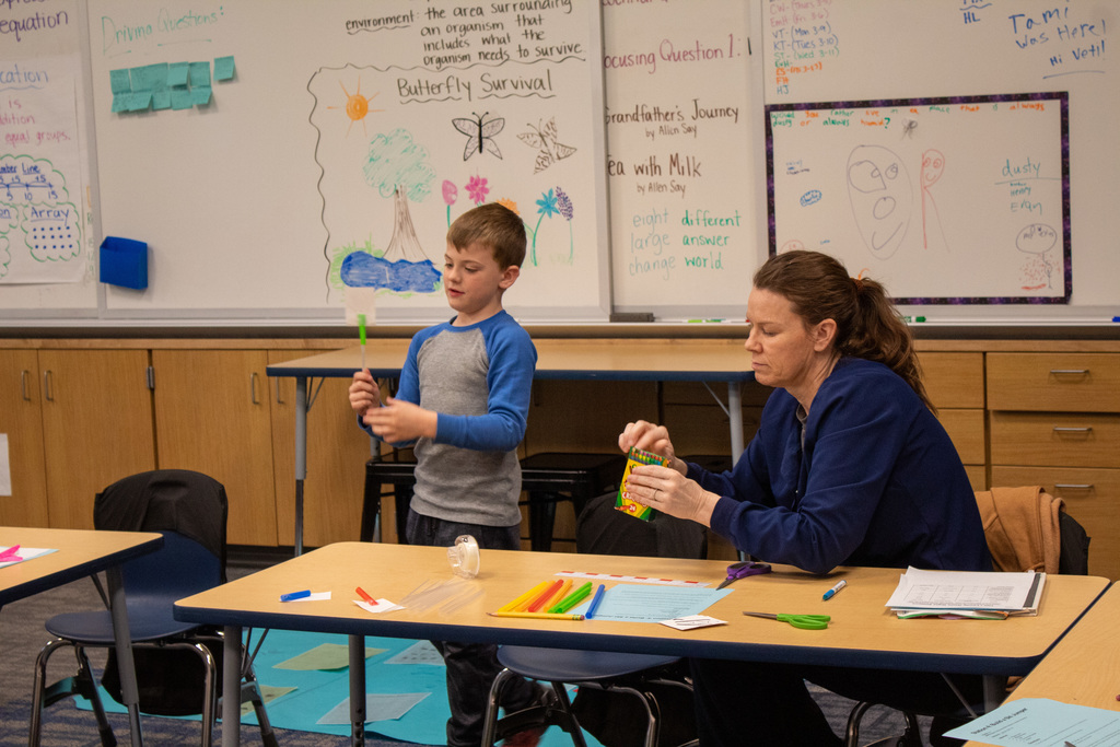 Young male student sitting with his mom at a desk
