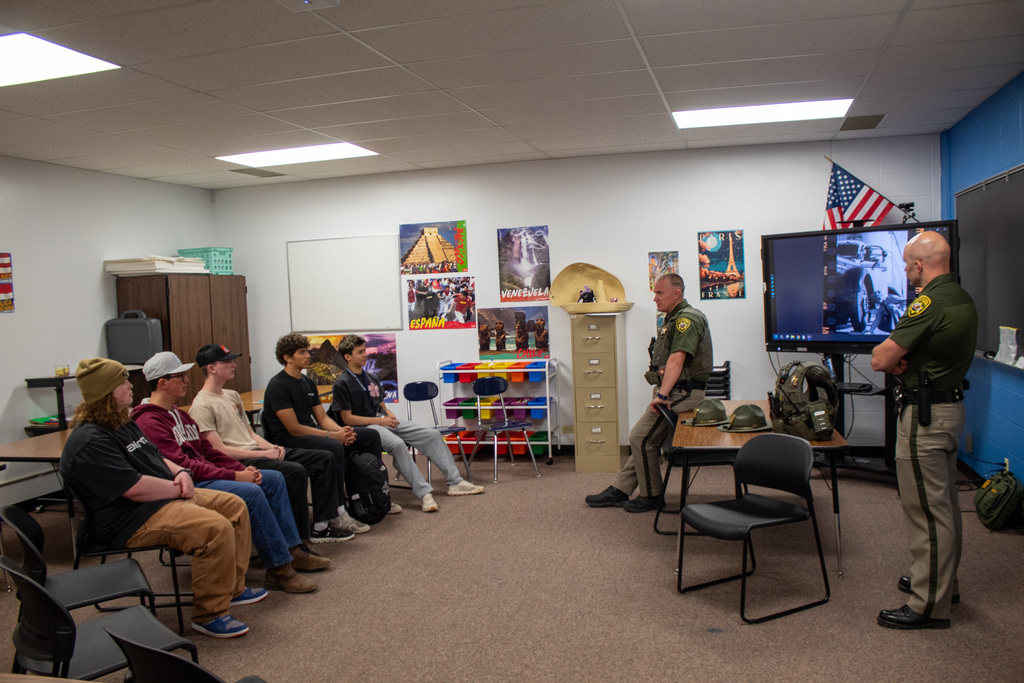 Five young men sitting talking to a highway patrolman