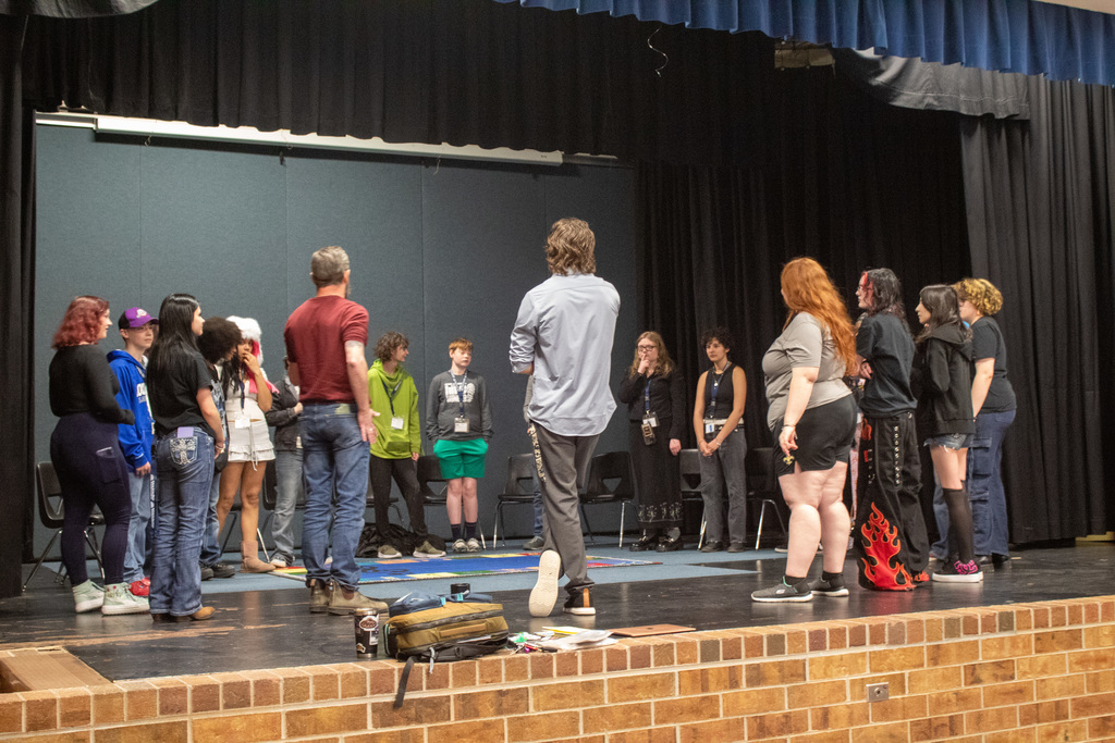 Group of young adults standing in a circl on stage