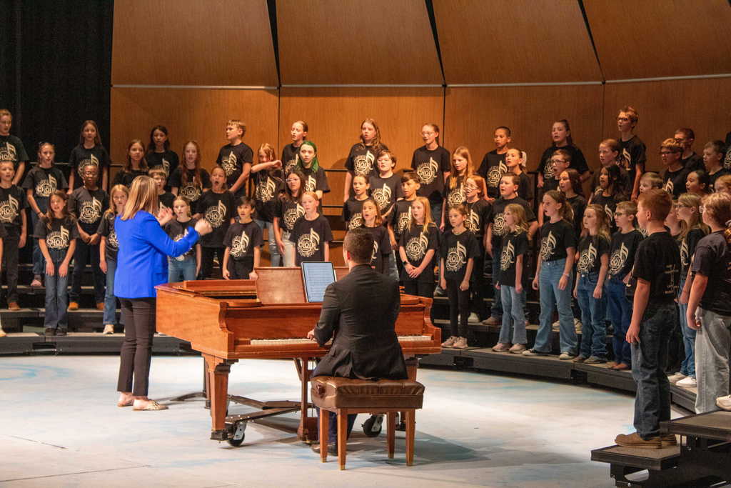 Students in choir singing and dancing on stage