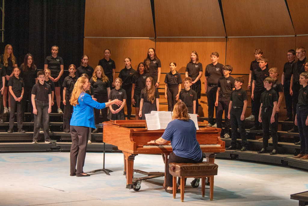 Students in choir singing and dancing on stage