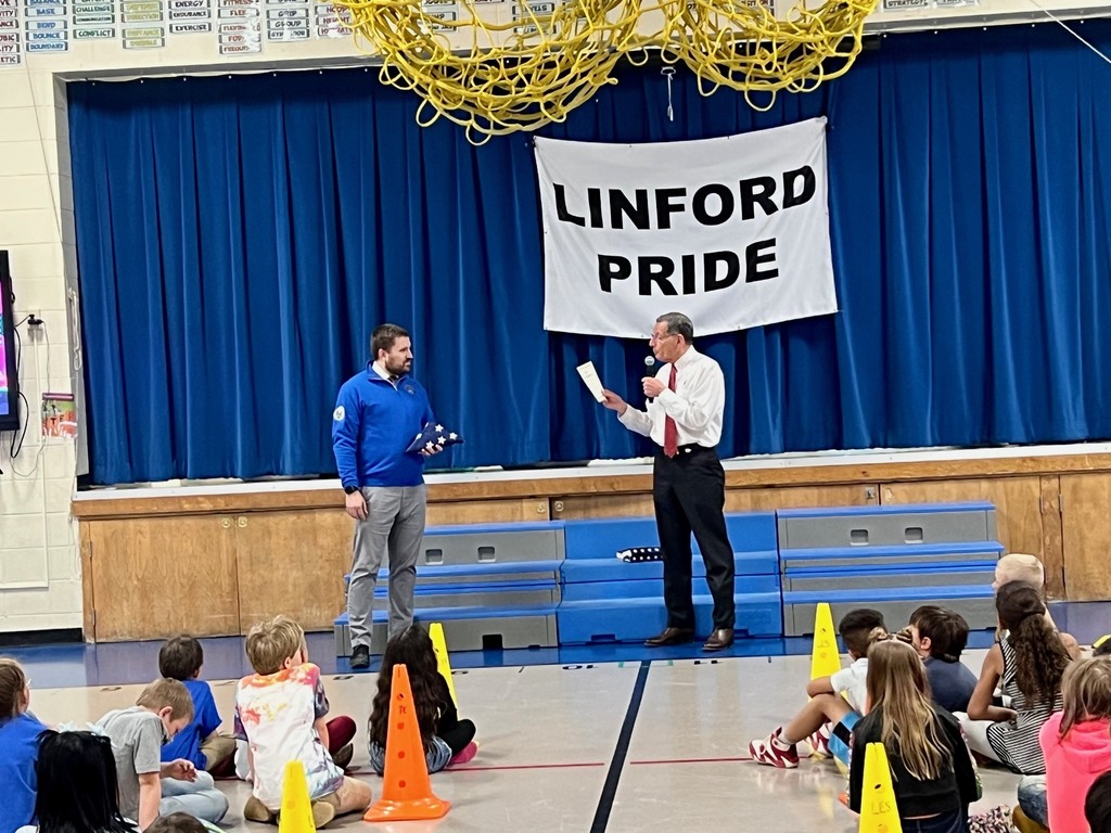 Man in white shirt and slacks talking to a man in slacks and a blue shirt
