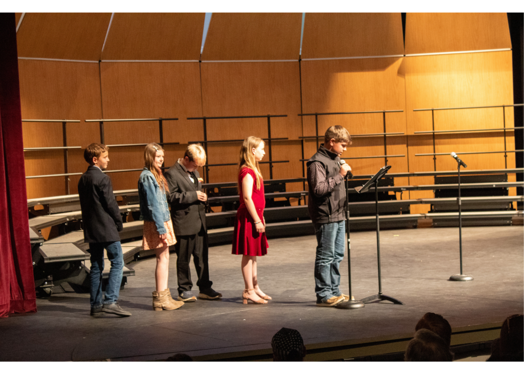 Four students lined up to talk at a micrphone