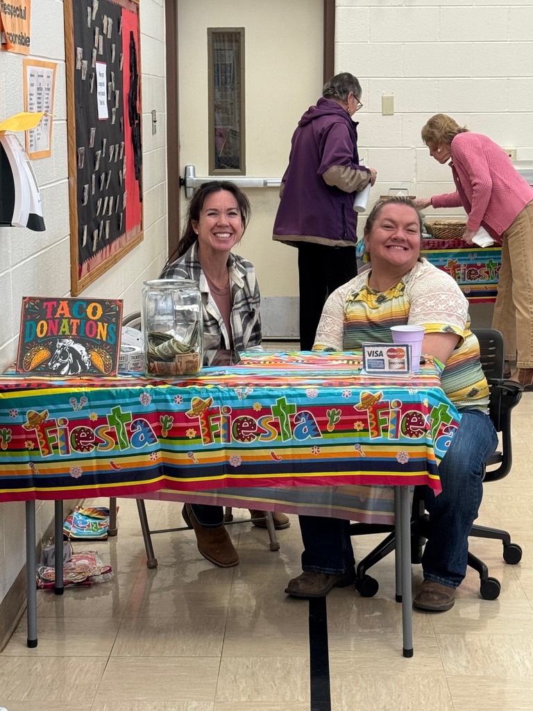 Two women sitting at a donation table smiling