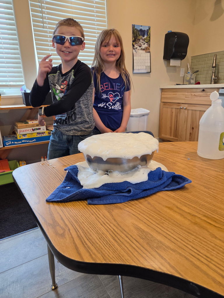 Young male and female student standing next to bowl full of bubbles
