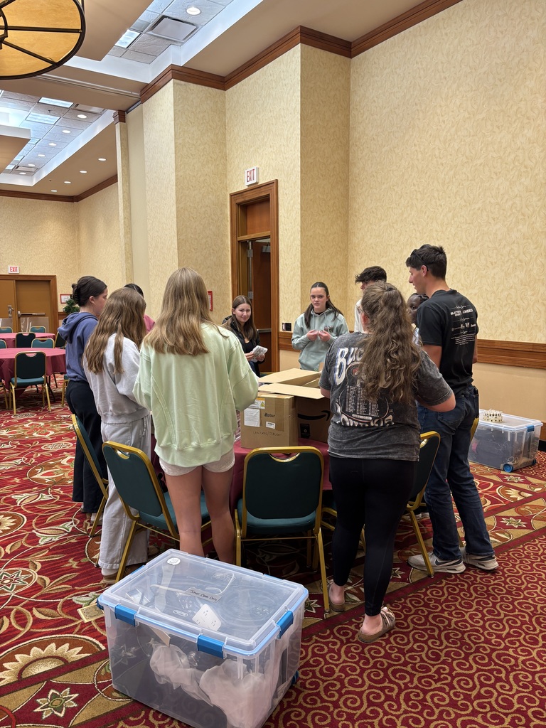 Group of high school students standing around a table preparing deocrations