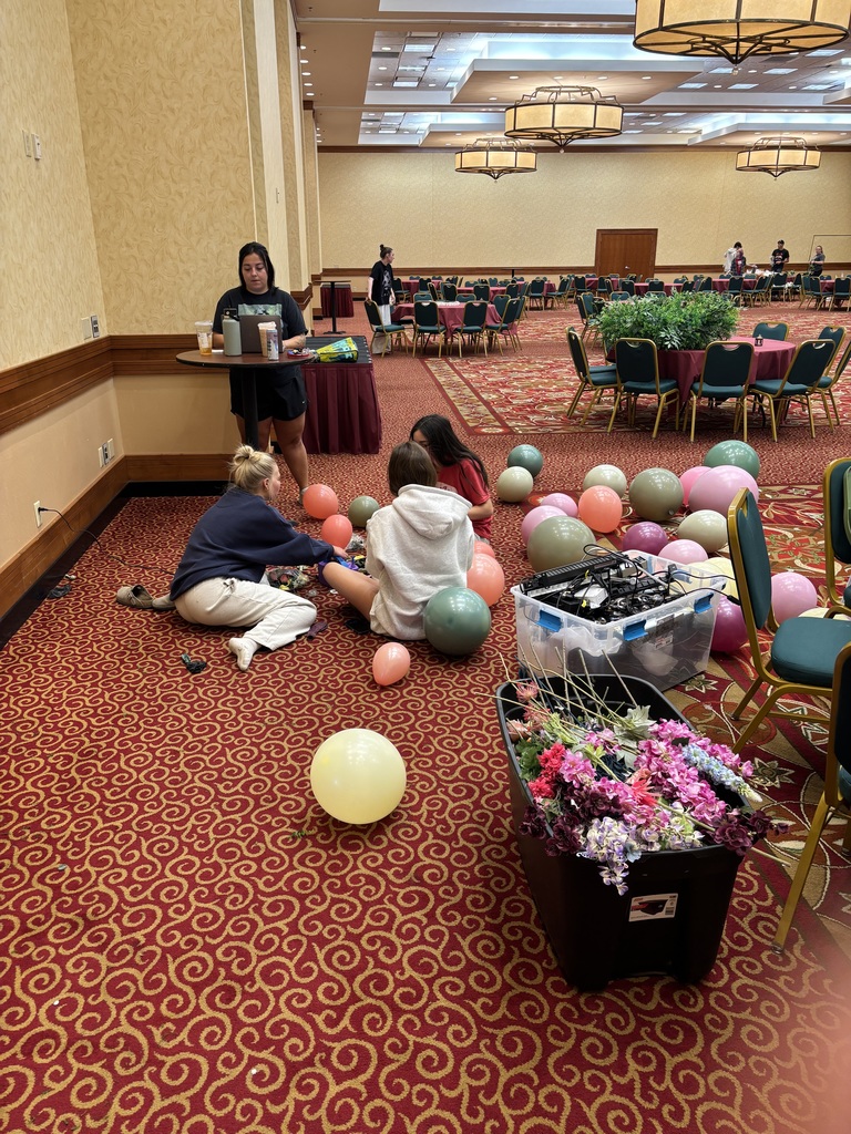 Students sitting on the floor blowing up baloons
