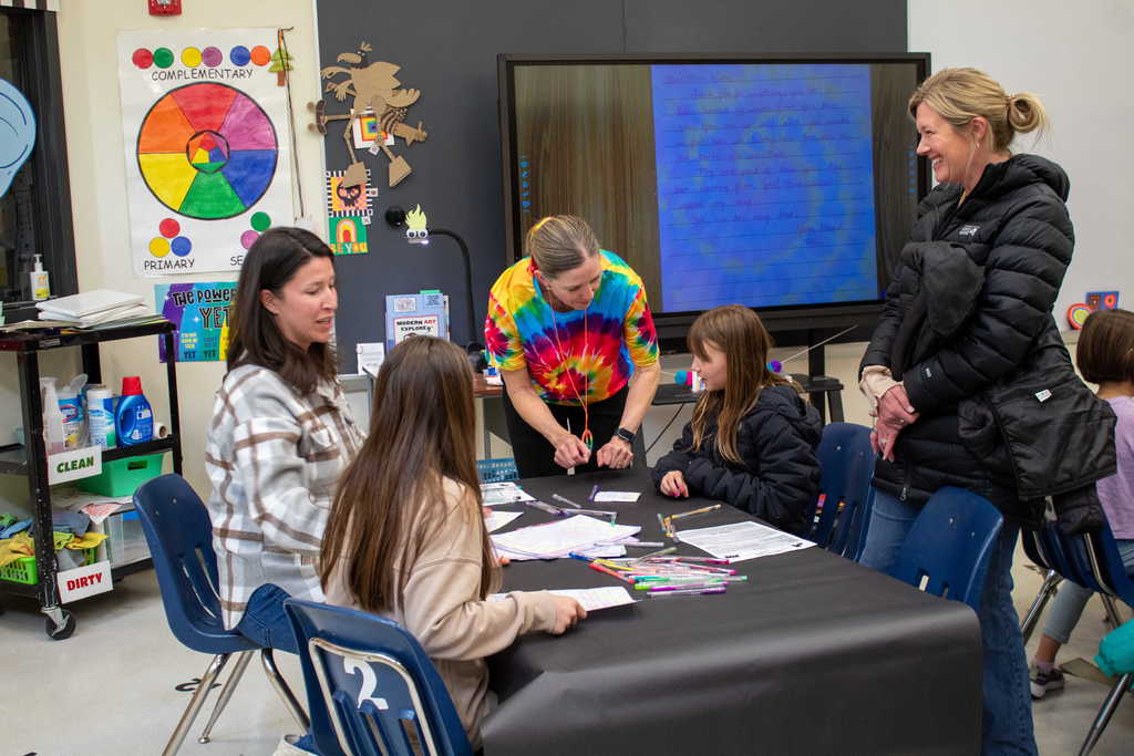 Women and children sitting around table laughing and doing crafts