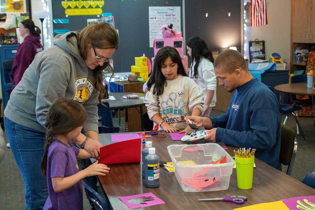 Students and parents gathered around a table doing crafts