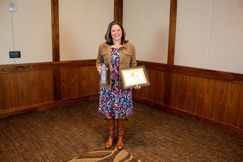 Women in bright colored dress with tall boots holding a certificate
