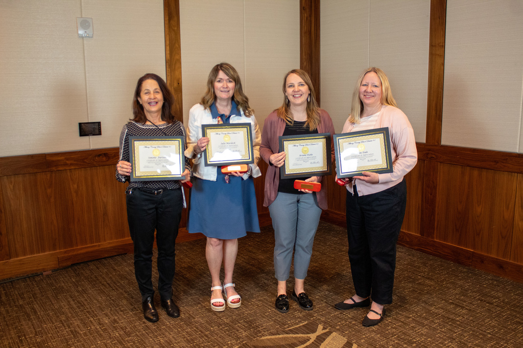 Four women holding a certificate and red boxes