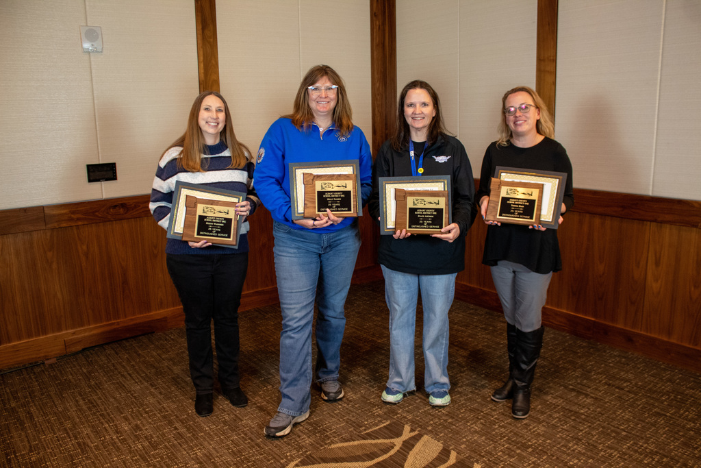 Four women standing holding plaques