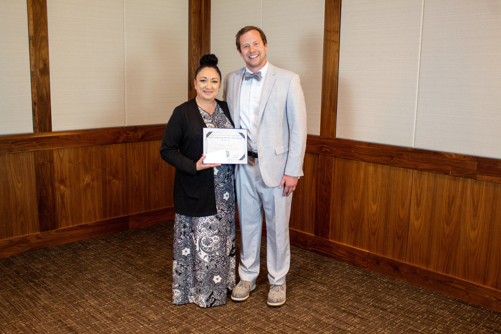 Man in a suit standing next to a woman in a dress with a cardigan