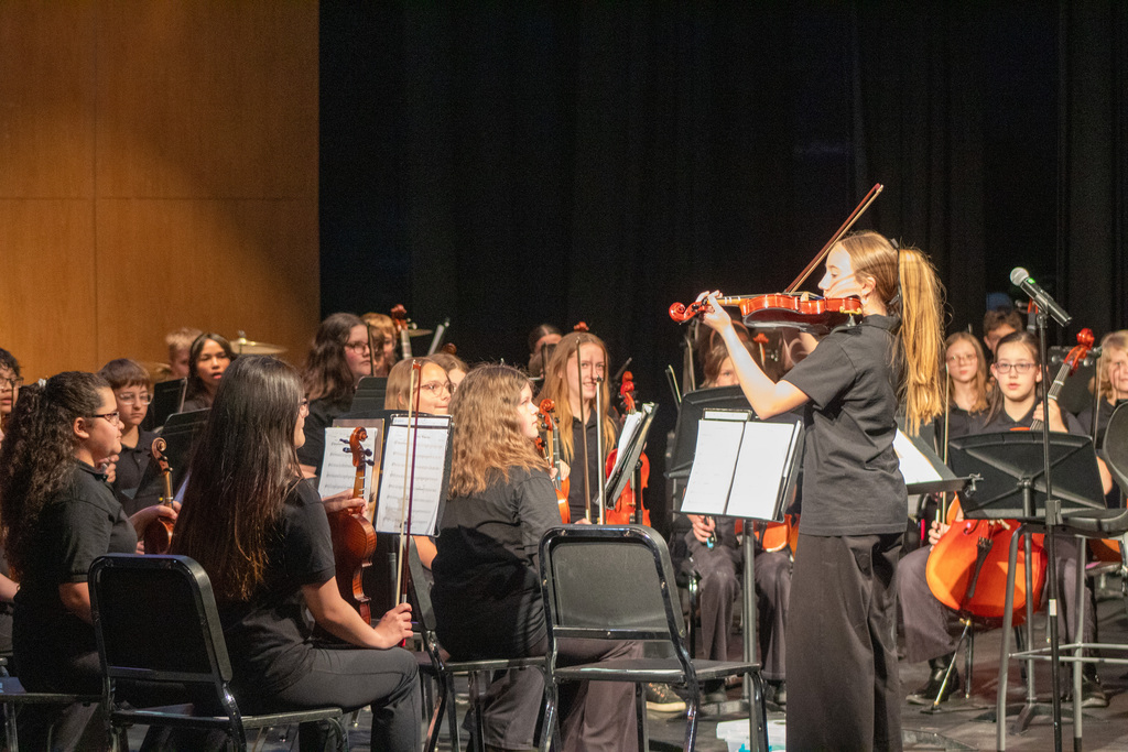 Blonde female student standing to lead orchestra