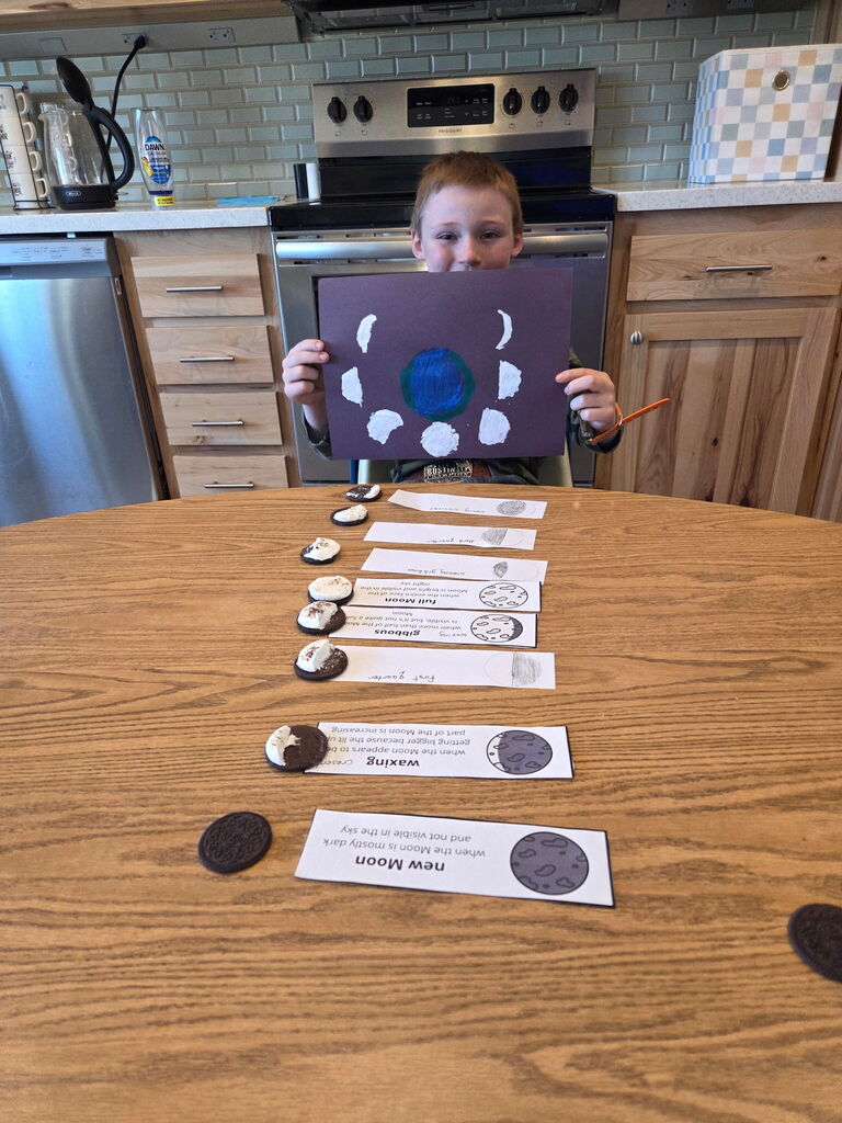 Young boy holding a paper showing the different moon cycles