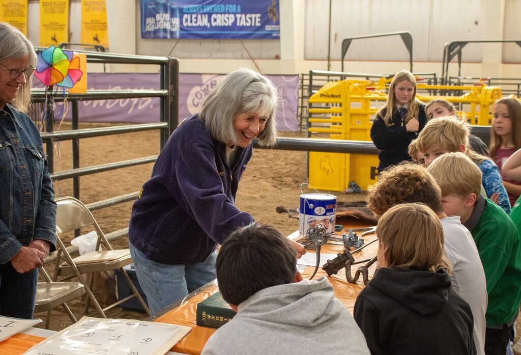Woman in blue jacket showing kids a branding iron