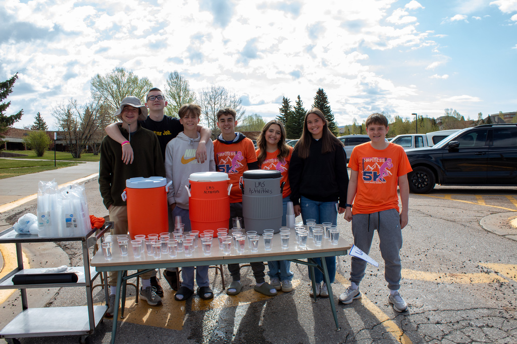 Group of student standing behind a table of water jugs and cups