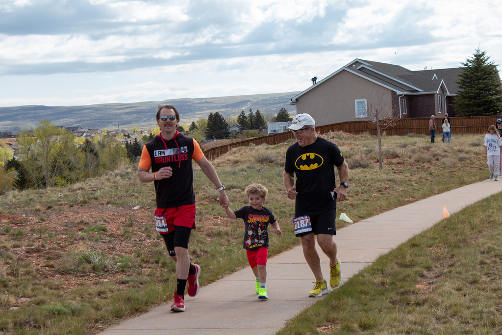 Two men running alongside young boy