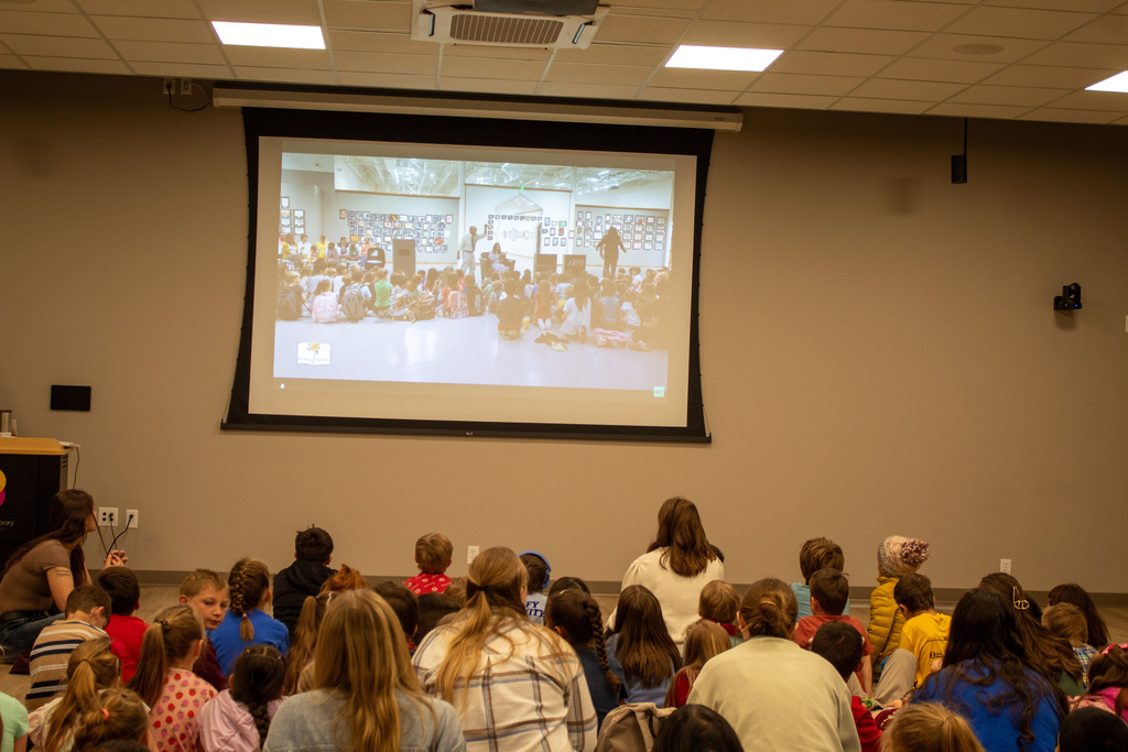 Students sitting on the floor looking at a projector
