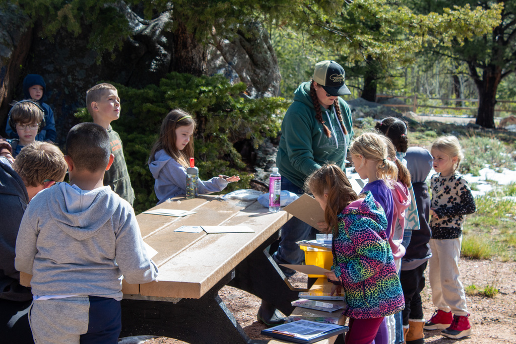 Students gathered around a picnic table talking to teacher