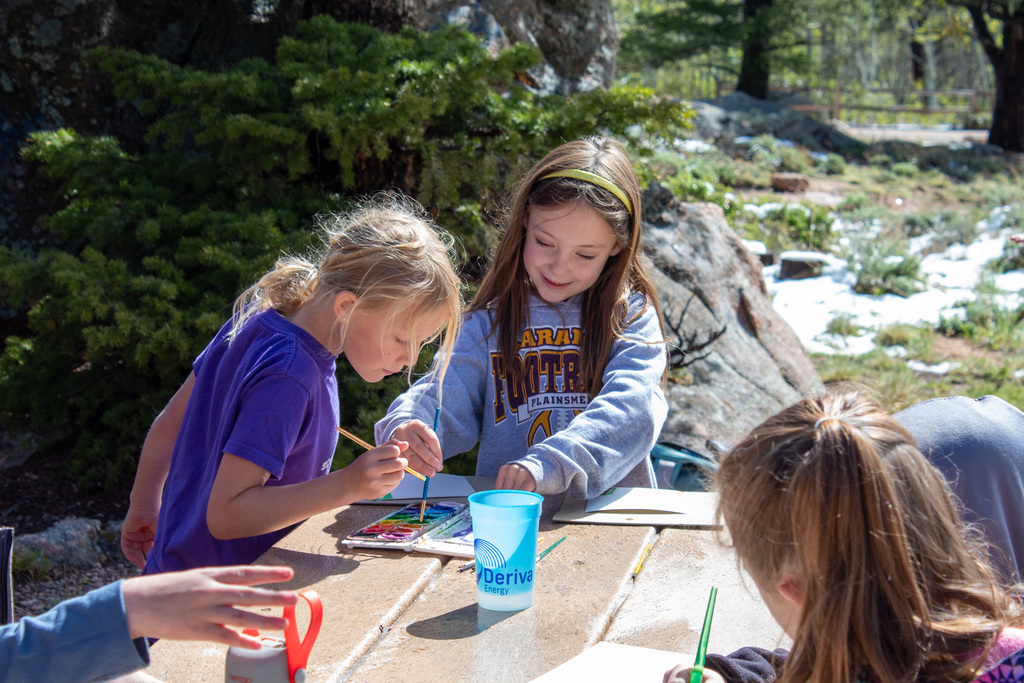 Two young girls painting at a picnic table