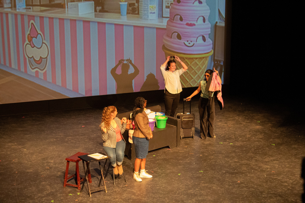 Four women on stage standing in front of a fake ice cream stand