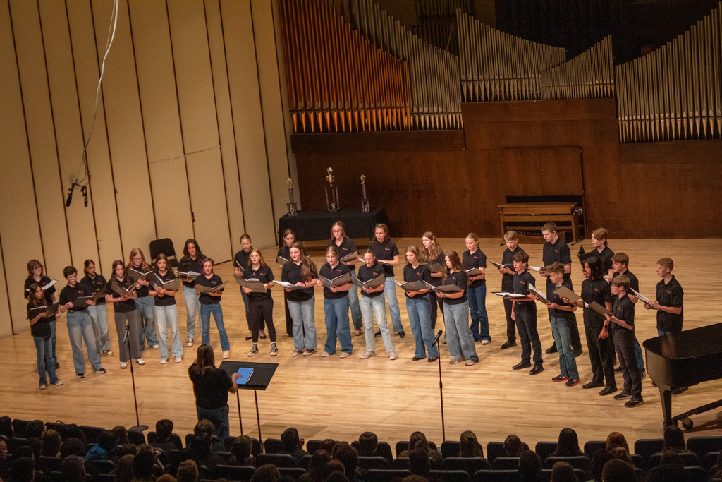 Group of young men and woman standing on stage singing