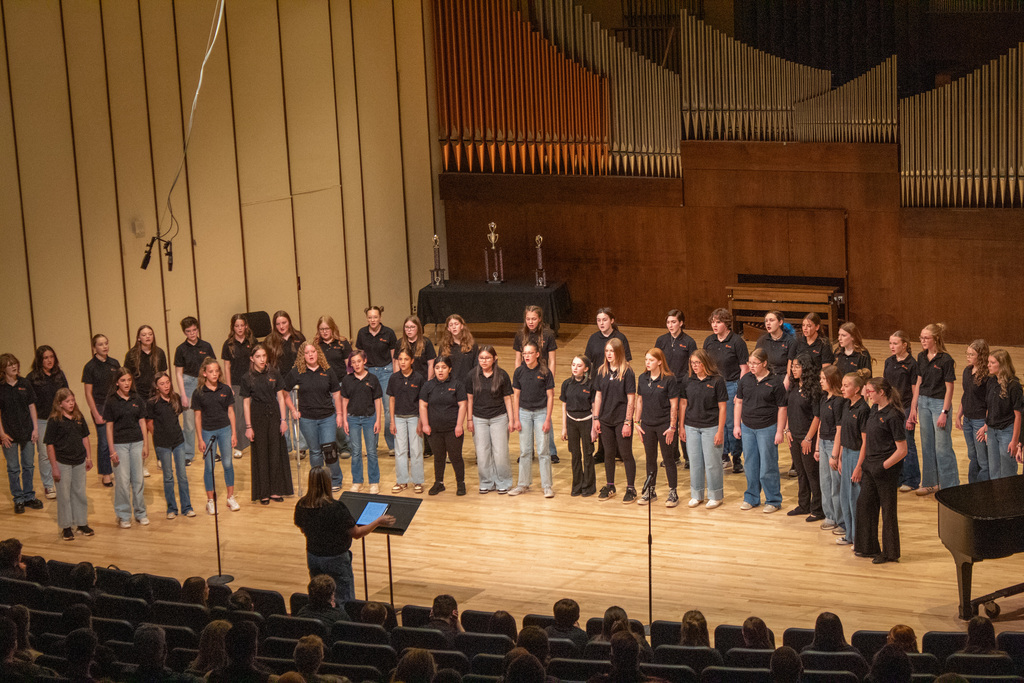 Group of young men and woman standing on stage singing