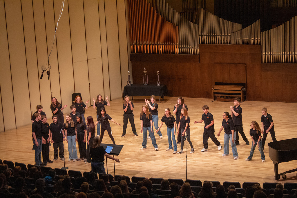 Group of young men and woman standing on stage singing