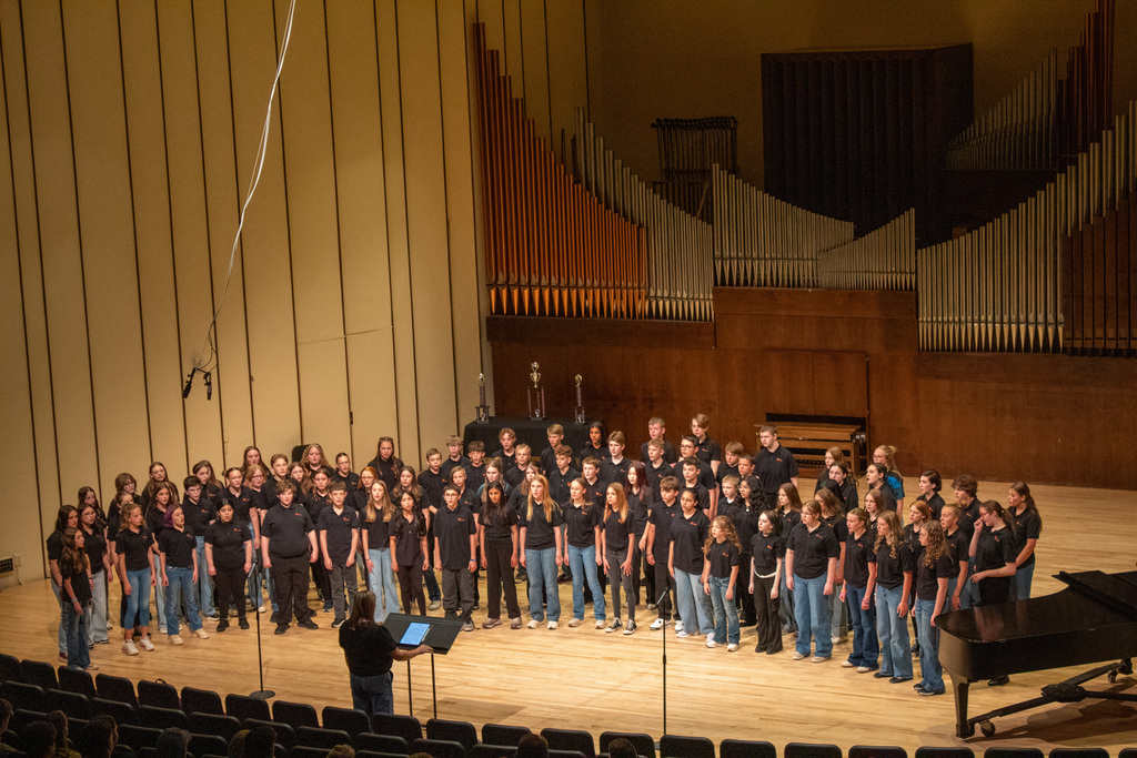 Group of young men and woman standing on stage singing
