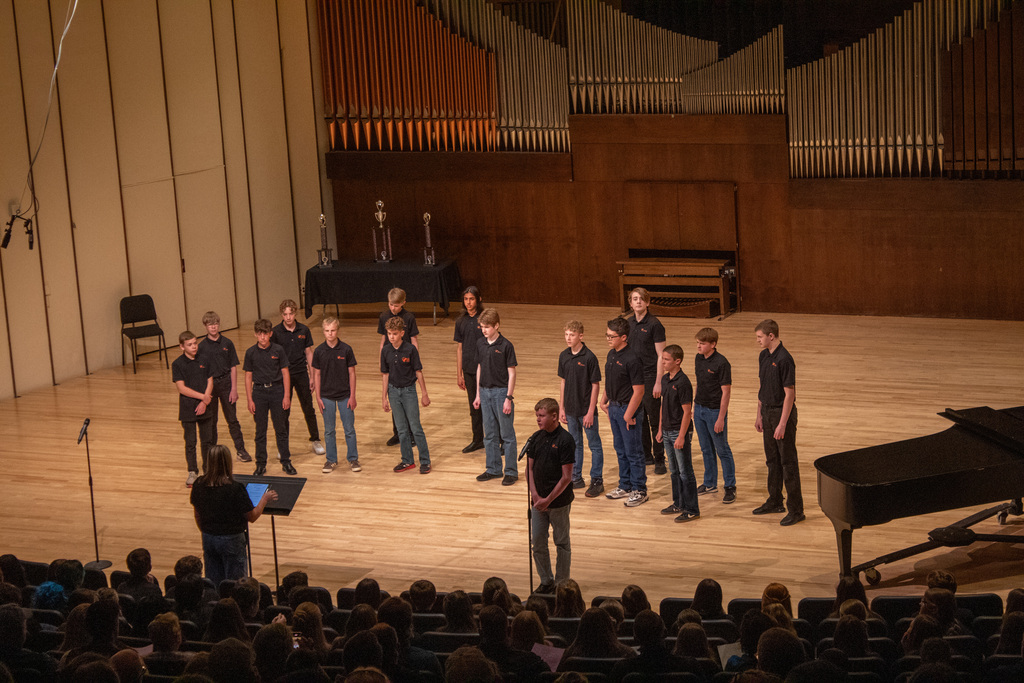 Group of young men and woman standing on stage singing
