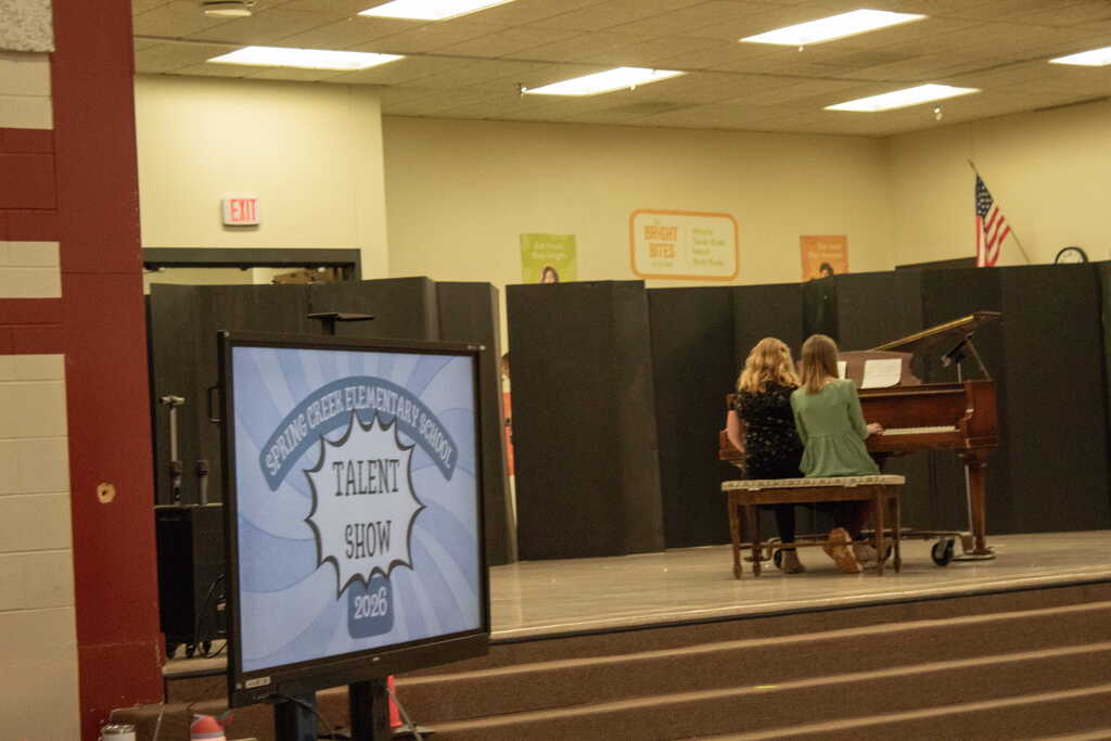 Two girls sitting next to each other playing the piano