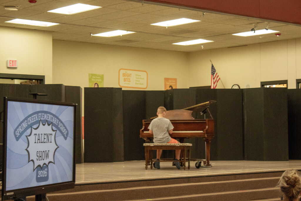 Young boy in gray playing the piano
