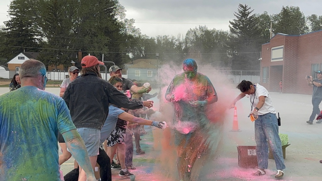Man covered in colored powder running through a crowd