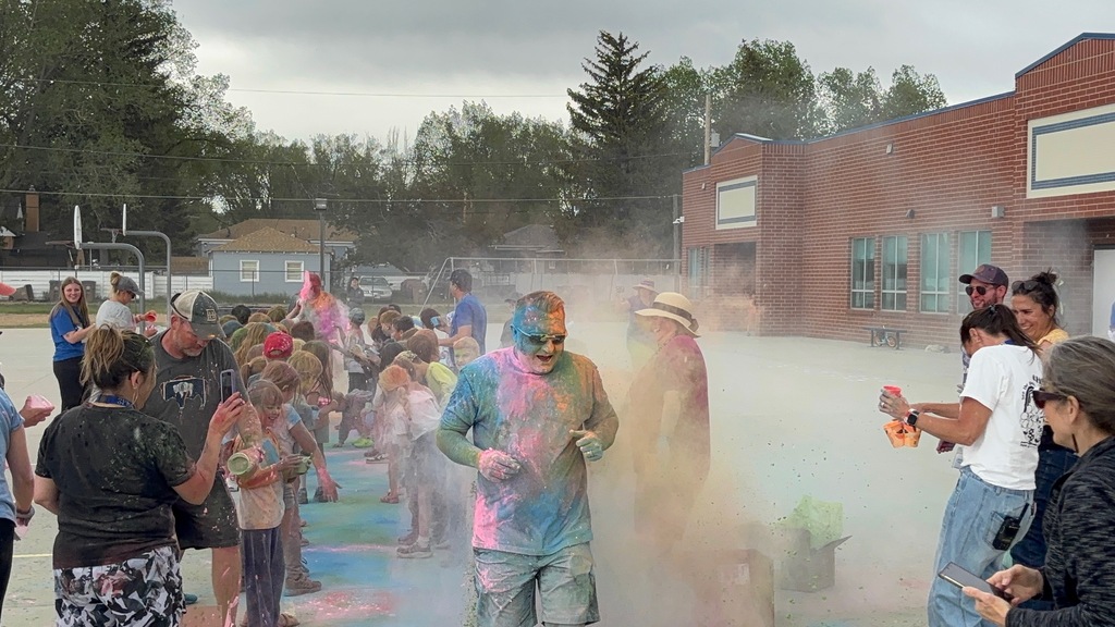 Man covered in colored powder running through a crowd