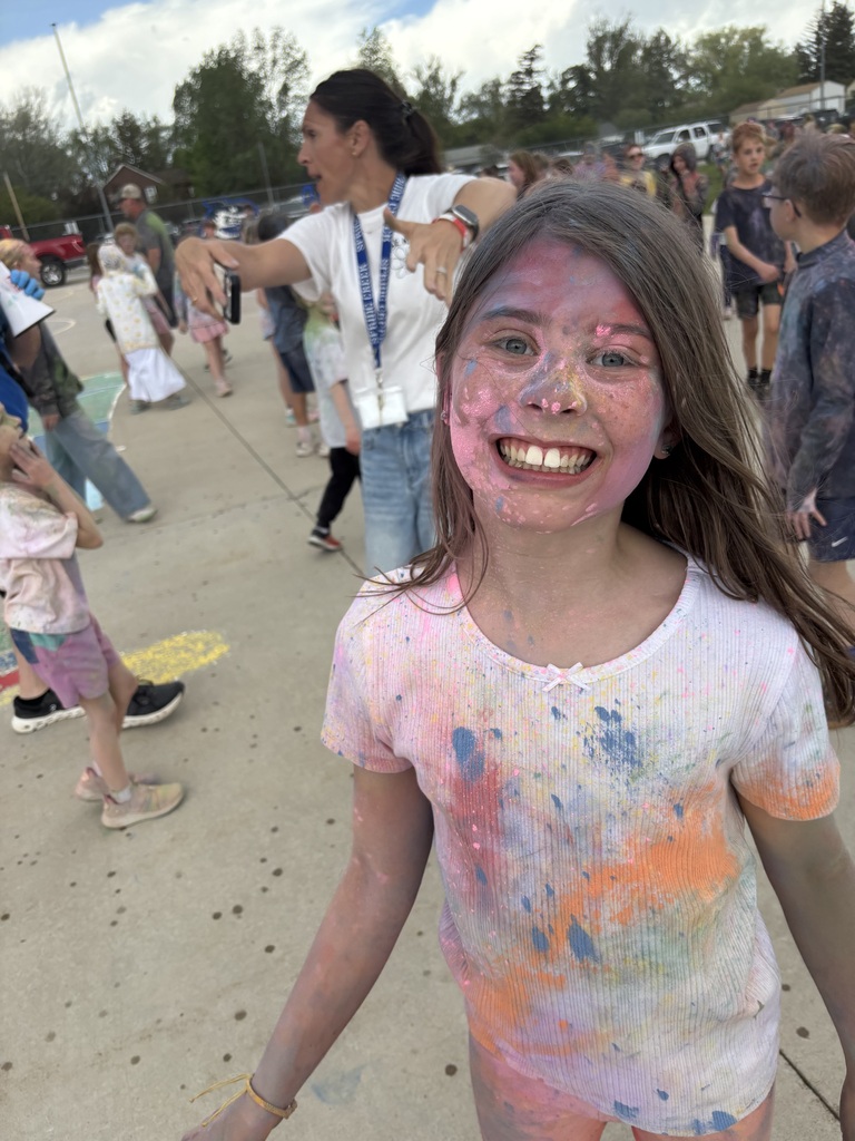 Young girl with brown hair and white shirt covered in color powder