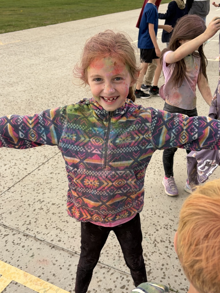 Young girl with blonde hair and aztec hoodie covered in color powder
