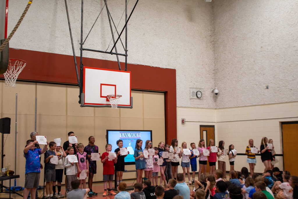 Group of students holding certificates standing in a line in a gym