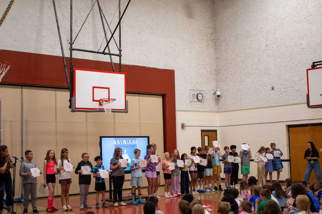 Group of students holding certificates standing in a line in a gym