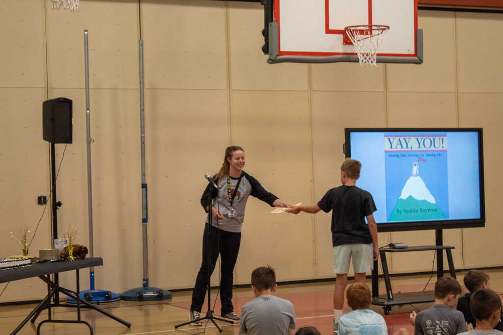 Female teacher handing young boy certificate
